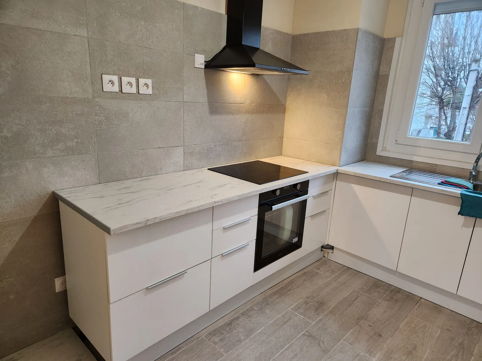 Cuisiniste Montpellier – cuisine blanche four noir hotte plan marbre carrelage gris